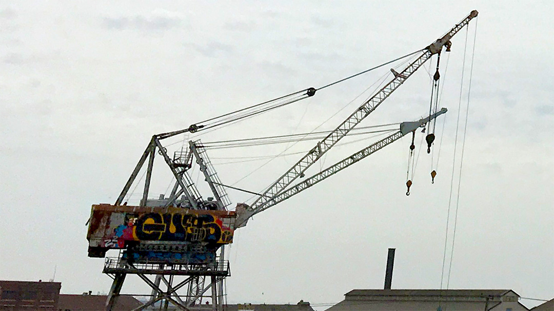 A crane in strong wind, its cables at slight angles in the force instead of hanging straight under gravity&rsquo;s influence.